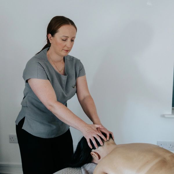 Woman giving a head massage to a lying client during cancer journey