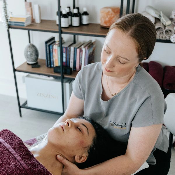 Therapist giving a relaxing neck massage to a client with cancer.