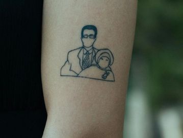 Minimalist tattoo of a man and woman on a forearm.