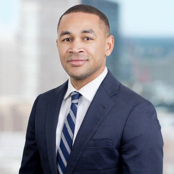 Professional portrait of a man in a navy suit and striped tie.