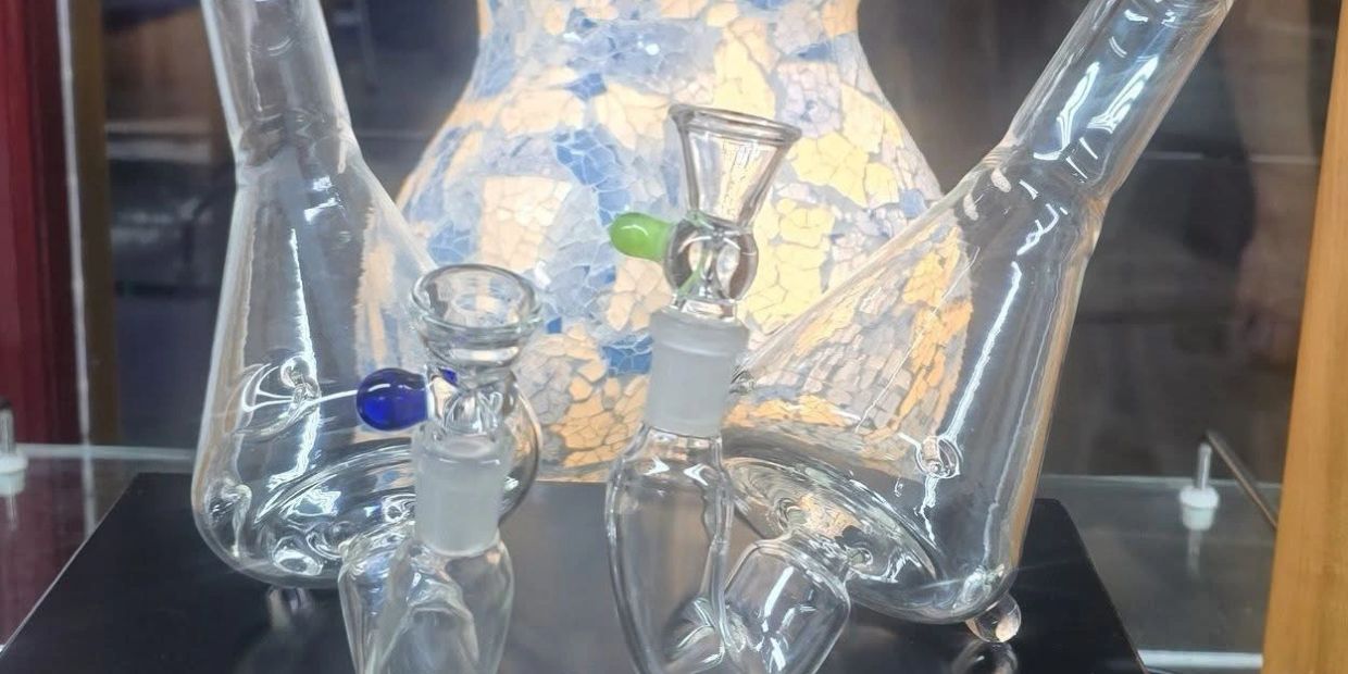 Two glass bongs with colored tips on black surface.