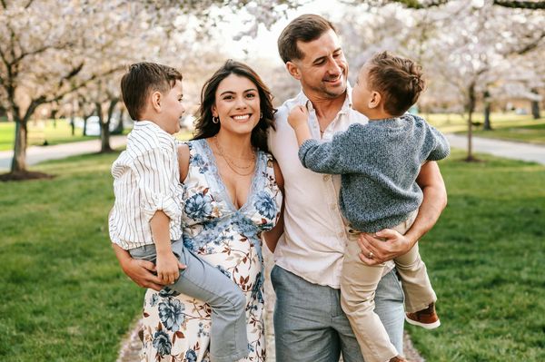 Happy family enjoying time outdoors with blooming trees in the background.