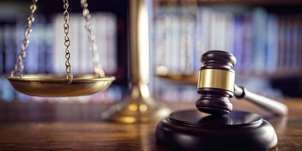 A judge's gavel and scales of justice on a wooden table.