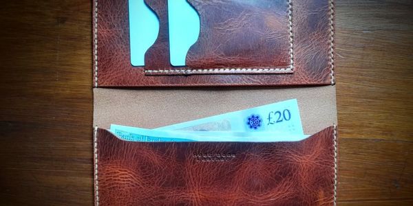 brown leather wallet showing bank cards and cash