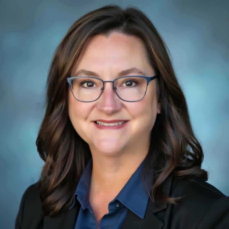 Professional woman with glasses smiling against a blue background.