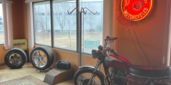 Vintage motorcycle inside a room with large windows and neon sign.
