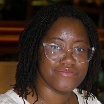 Smiling woman with glasses and dreadlocks.