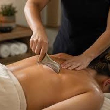 Person receiving a back massage with a scraping tool.