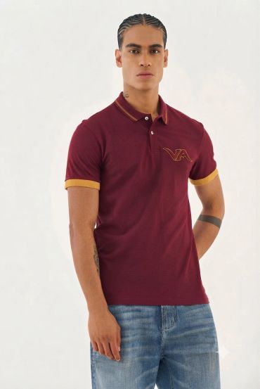 Bordo ve hardal detaylı polo tişört giymiş genç adam.