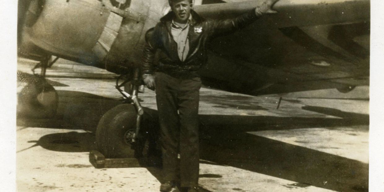 A man standing by a vintage airplane wing.