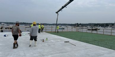 Construction workers pouring concrete on a waterfront site.