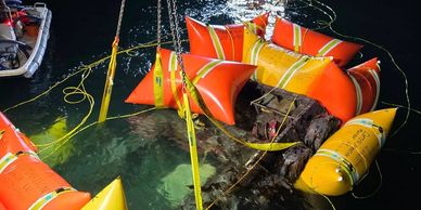 Nighttime underwater salvage operation with flotation devices and boats.