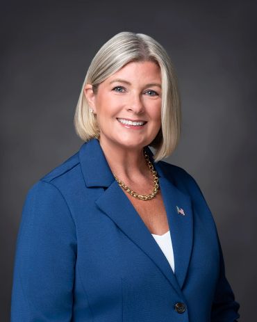 Professional portrait of a smiling woman in a blue blazer.