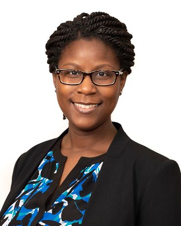 Smiling woman with glasses and braided hair.