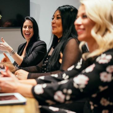 Three women engaging in a lively discussion at a meeting.