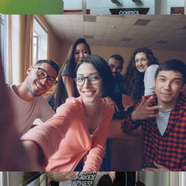 A group of six friends smiling and posing for a selfie indoors.