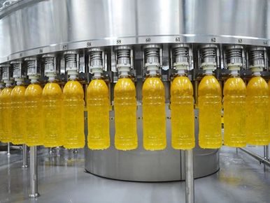 Bottles being filled with orange liquid on a production line.