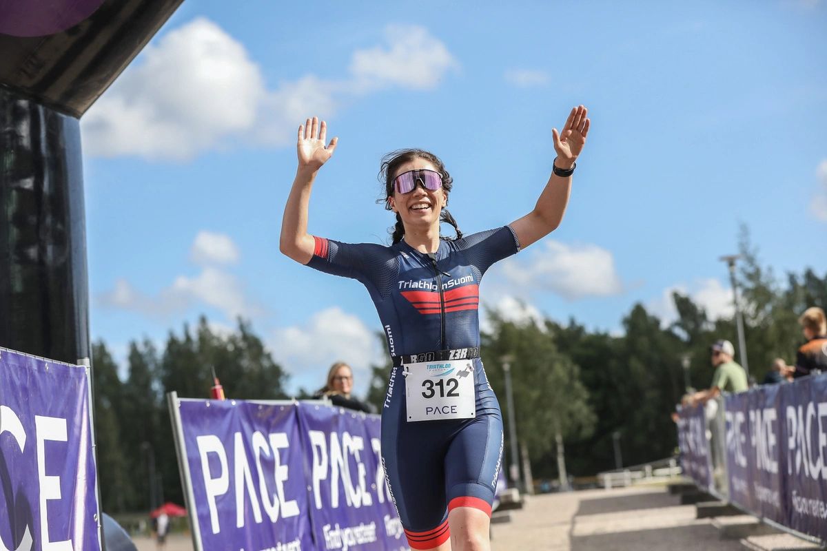 Athlete joyfully crosses the finish line of a triathlon race.