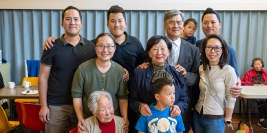 A multi-generational family posing together indoors, smiling warmly.