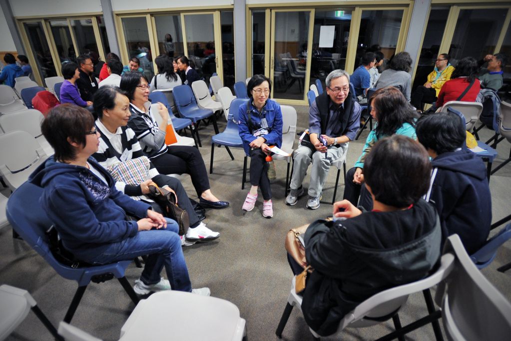 A group of people sitting in a circle having a discussion in a meeting room.