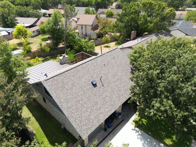 Aerial view of a suburban house with a large roof and surrounding greenery.