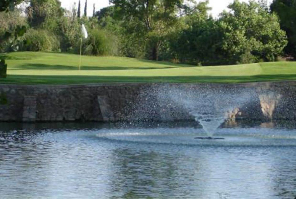 Water fountain spraying in a pond at a golf course.