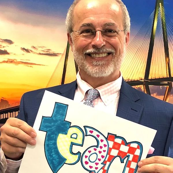 Smiling man holding colorful "team" sign.