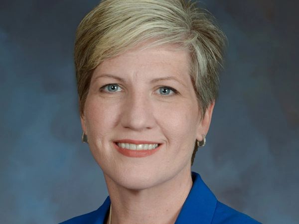 Professional headshot of a smiling woman with short blonde hair.