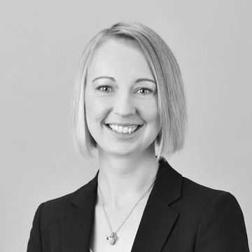 Professional woman with blonde hair smiling in a black blazer.