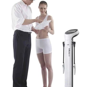 A man explaining body composition results to a woman next to an InBody 570 machine.