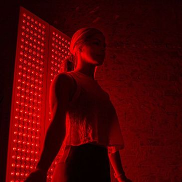 Woman illuminated by red light panels in a dark room.