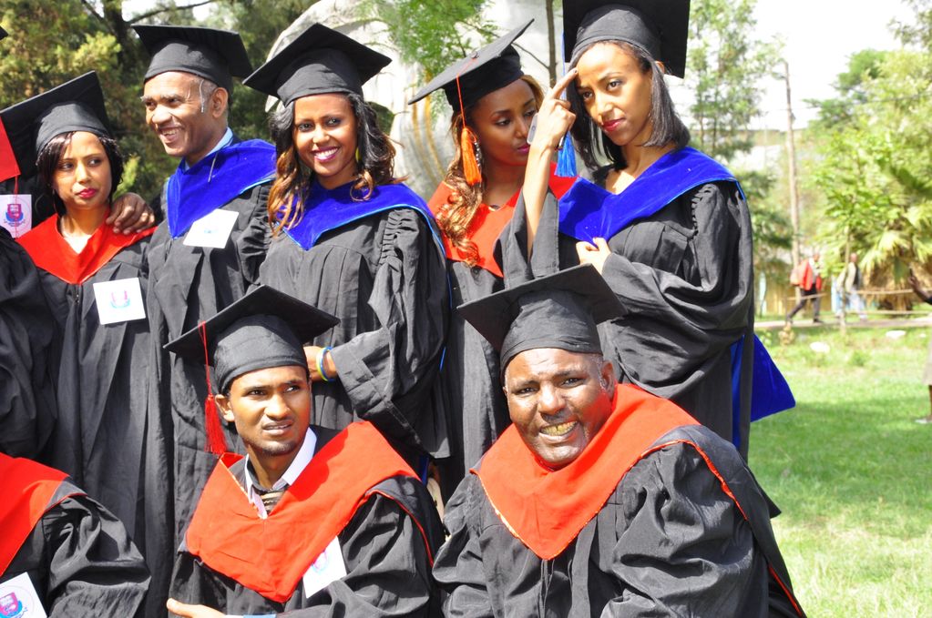 A group of diverse graduates posing outdoors in caps and gowns.