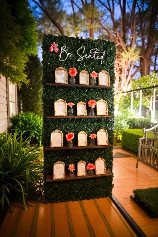 Elegant outdoor seating chart with floral decorations and gold-framed cards.