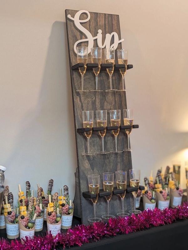 Elegant champagne display with snacks and bottled water on a decorated table.