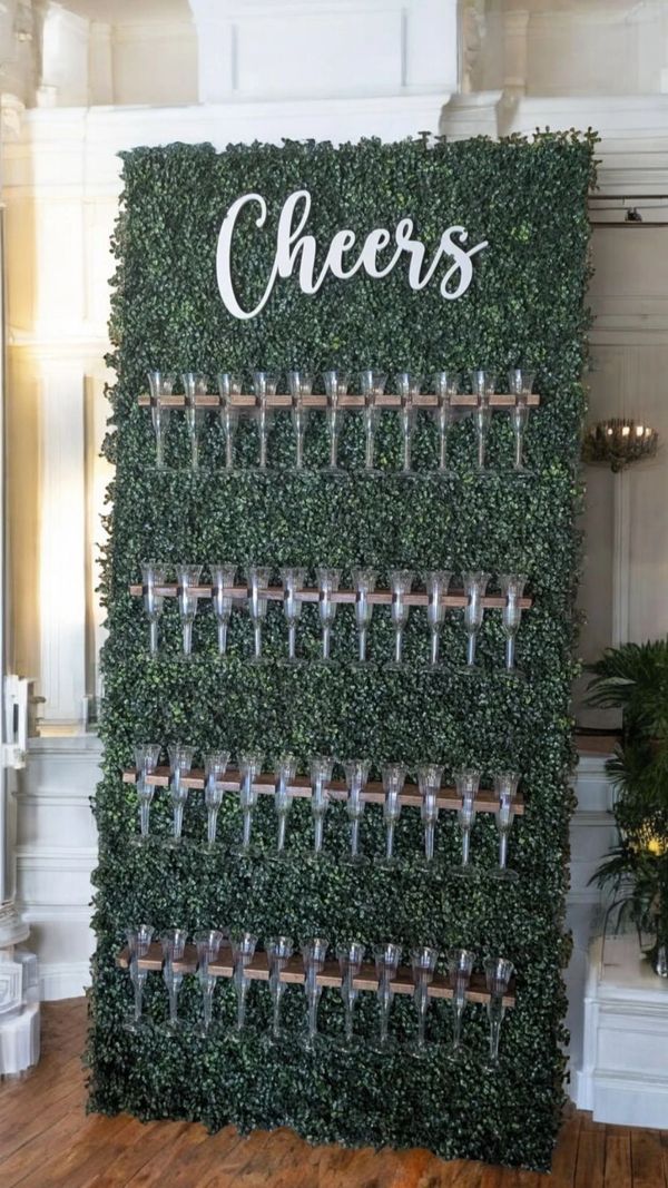 A green wall display with clear champagne glasses and "Cheers" sign.