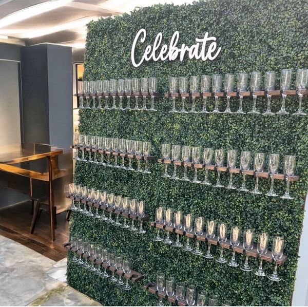 Green wall with 'Celebrate' sign and champagne glasses on wooden shelves.