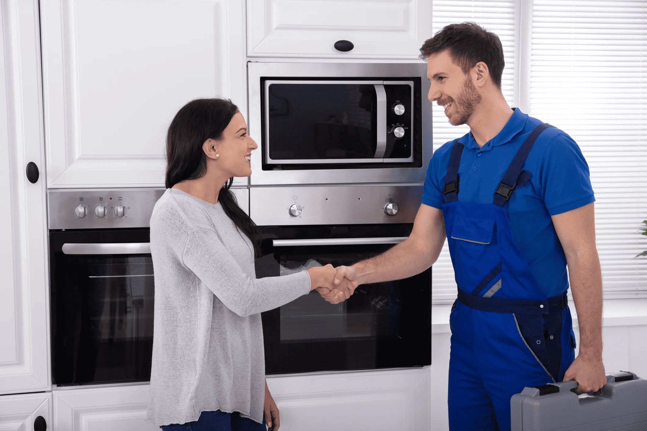 Woman shaking hands with a repairman in a kitchen. Professional Appliance Repair Services in Simcoe