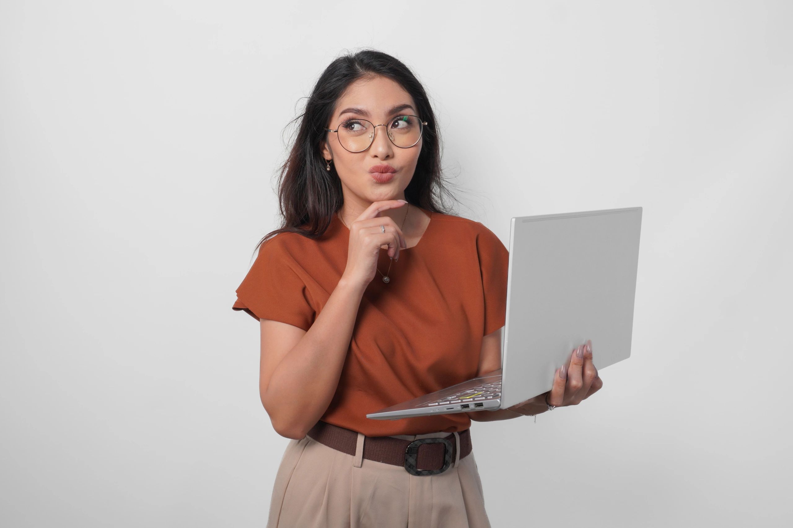 Woman thinking while using laptop, representing questions about work from home jobs”