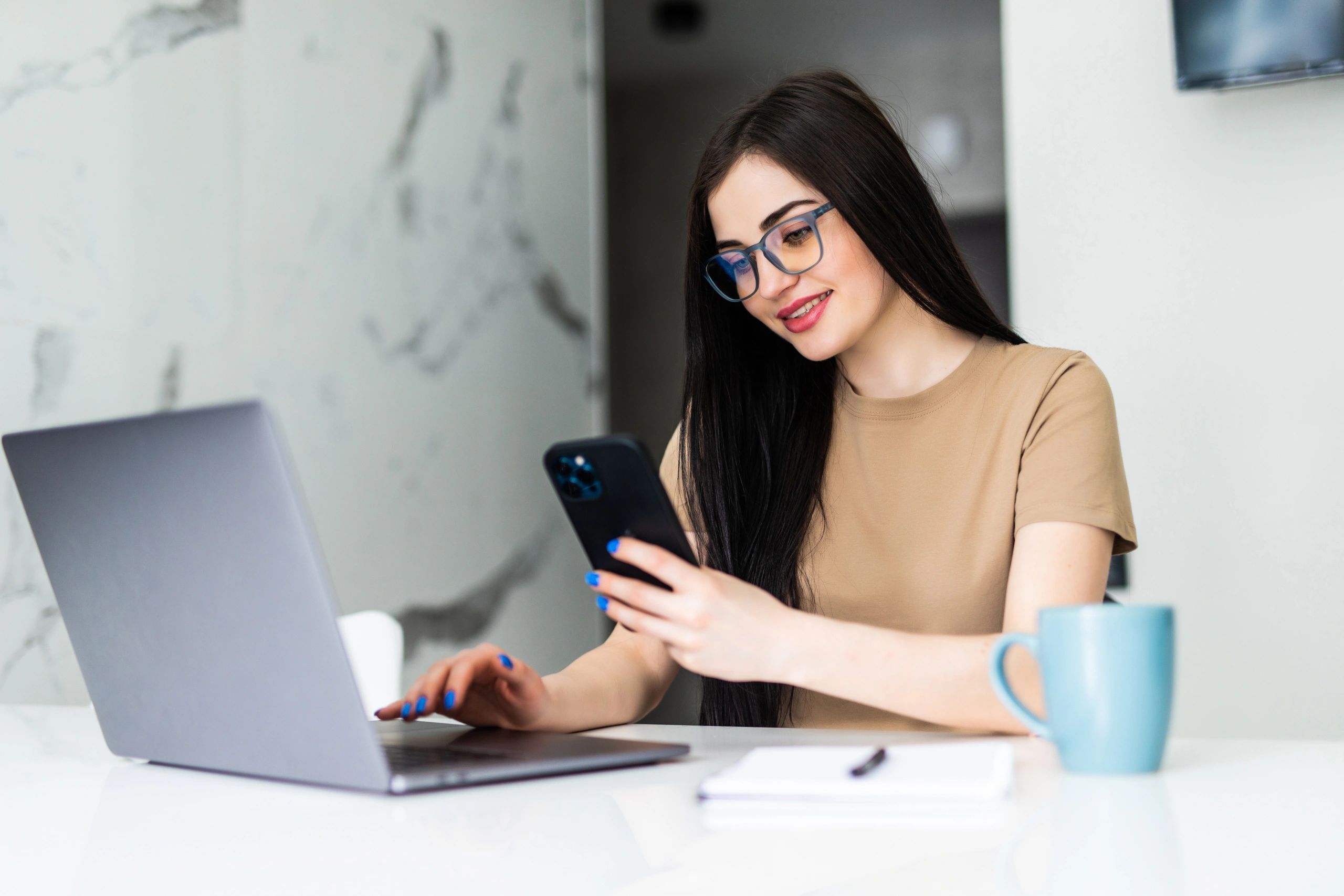 Woman using laptop and phone for flexible work from home job