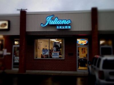 Juliano Salon storefront with neon signs at dusk.