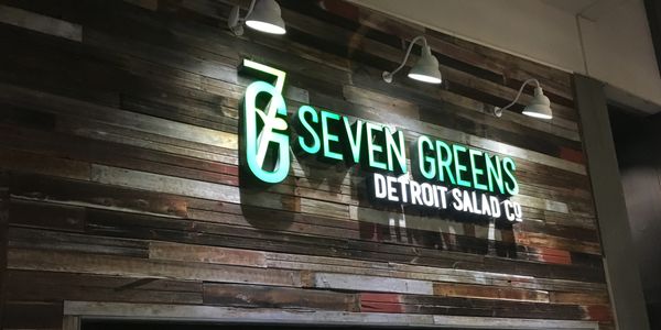 Seven Greens Detroit Salad Co. sign on wooden wall.