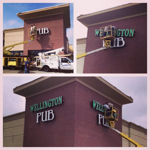 Workers installing a sign on a building.