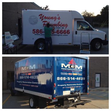Two plumbing and restoration service trucks parked outside buildings.