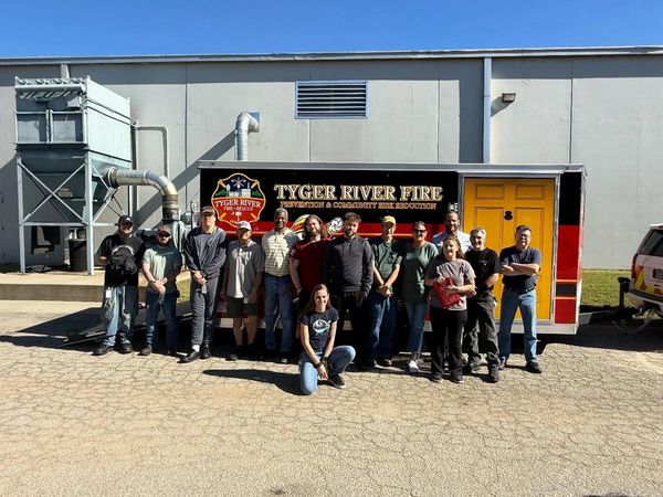 A group of people posing in front of a Tyger River Fire Prevention vehicle.