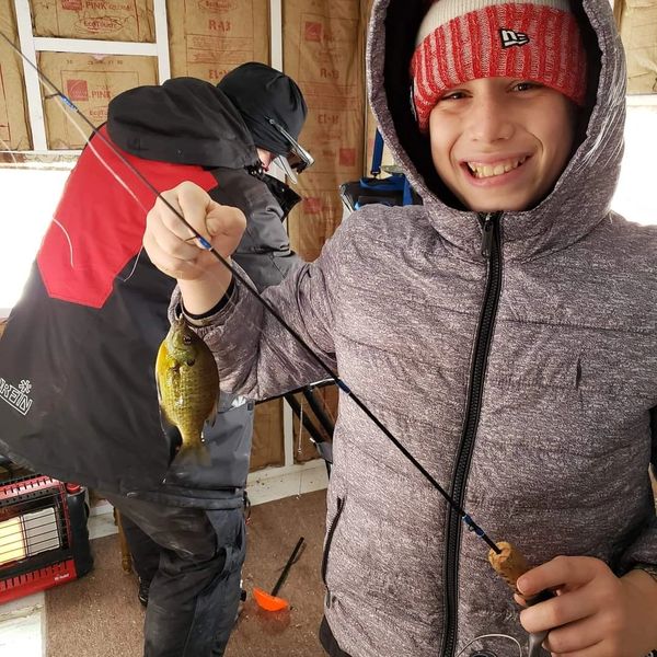 Kid ice fishing with ice fishing guide