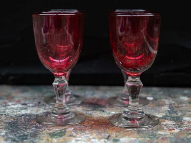 Two elegant red wine glasses on a textured surface.