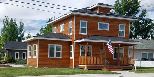 Modern two-story wooden house with an American flag on the porch.