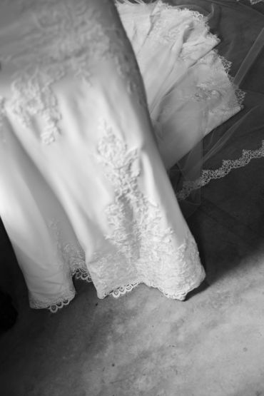Close-up of a white wedding dress with intricate lace details.