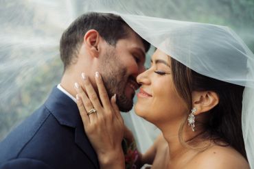 Bride and groom share an intimate moment under the veil.