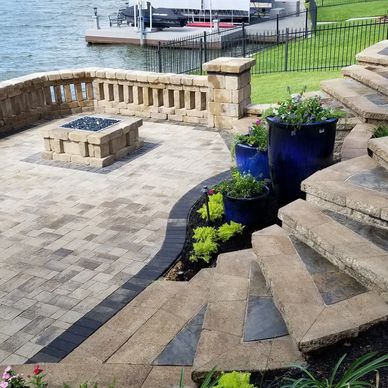Stone patio with stairs, blue planters, and a lake view.